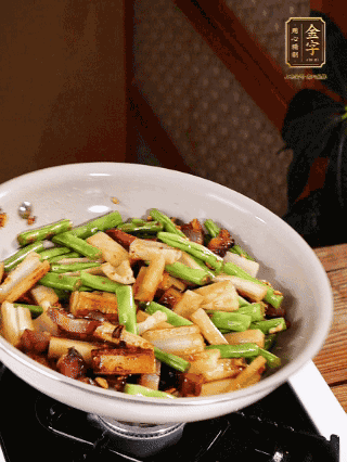 油熱下蒜末、干辣椒、醬肉煸炒出香味，依次下藕條、豆角翻炒均勻